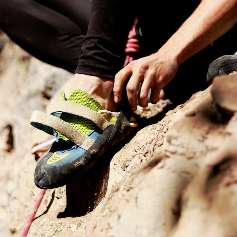 unpaired brown, green, and blue rock climbing shoe