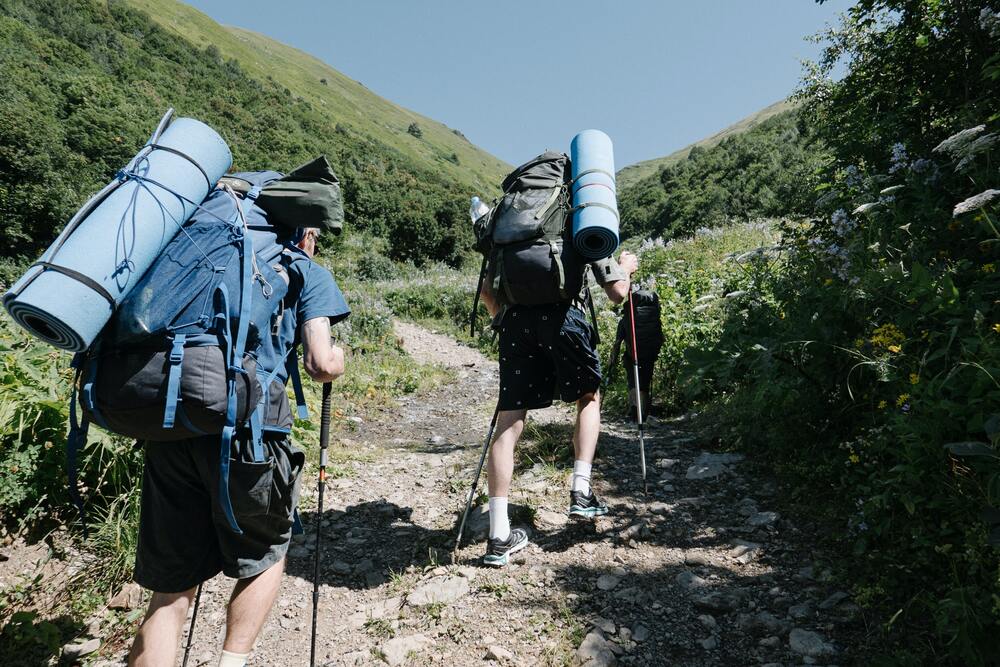 hikers going up mountain with trekking poles
