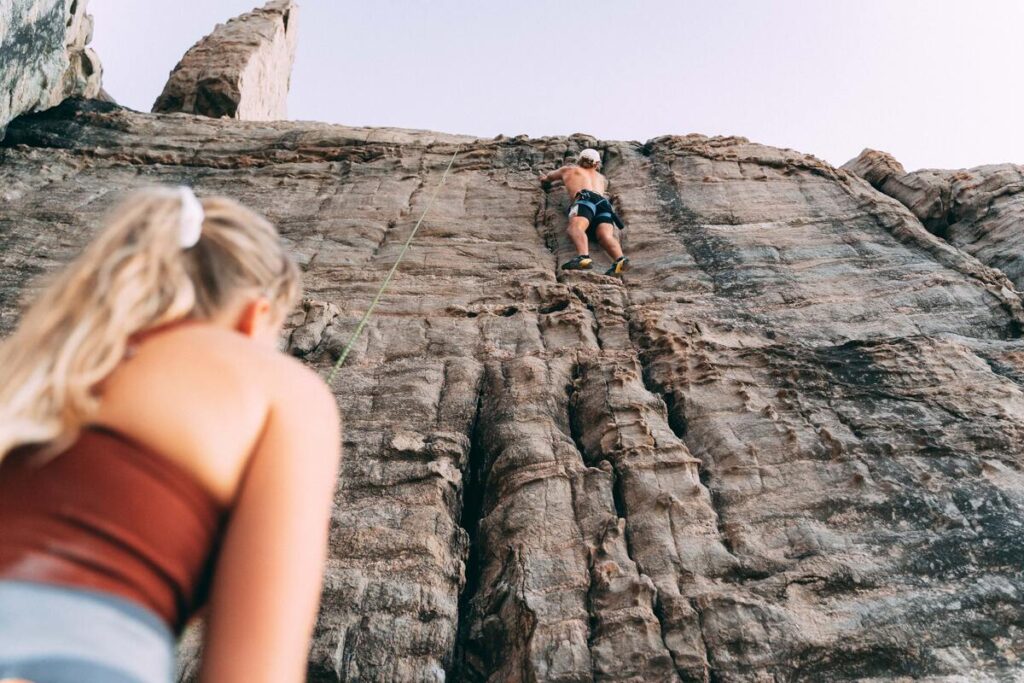 climber on rock face with partner looking up
